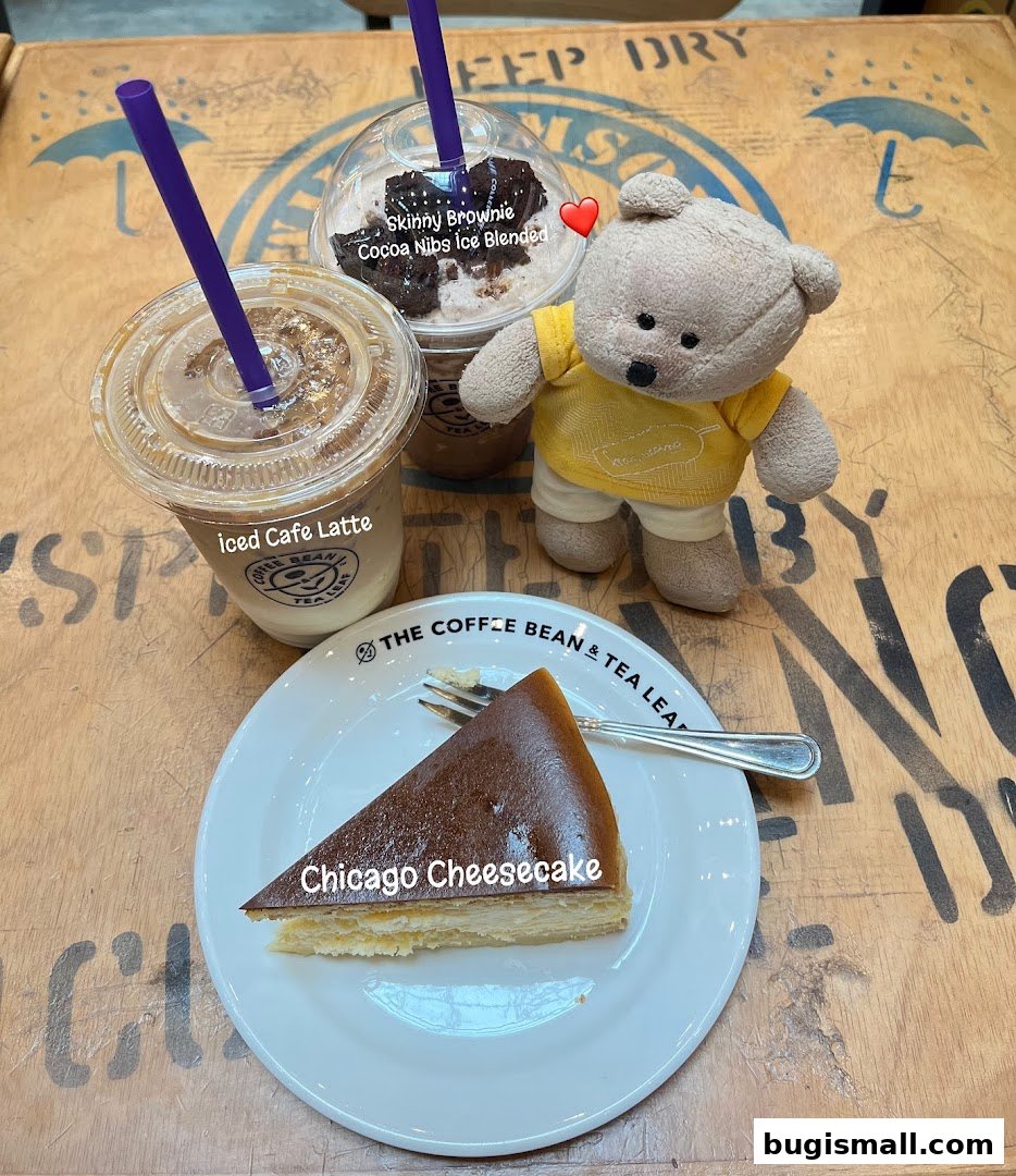 A teddy bear sits beside coffee drinks and a slice of cheesecake at The Coffee Bean & Tea Leaf.