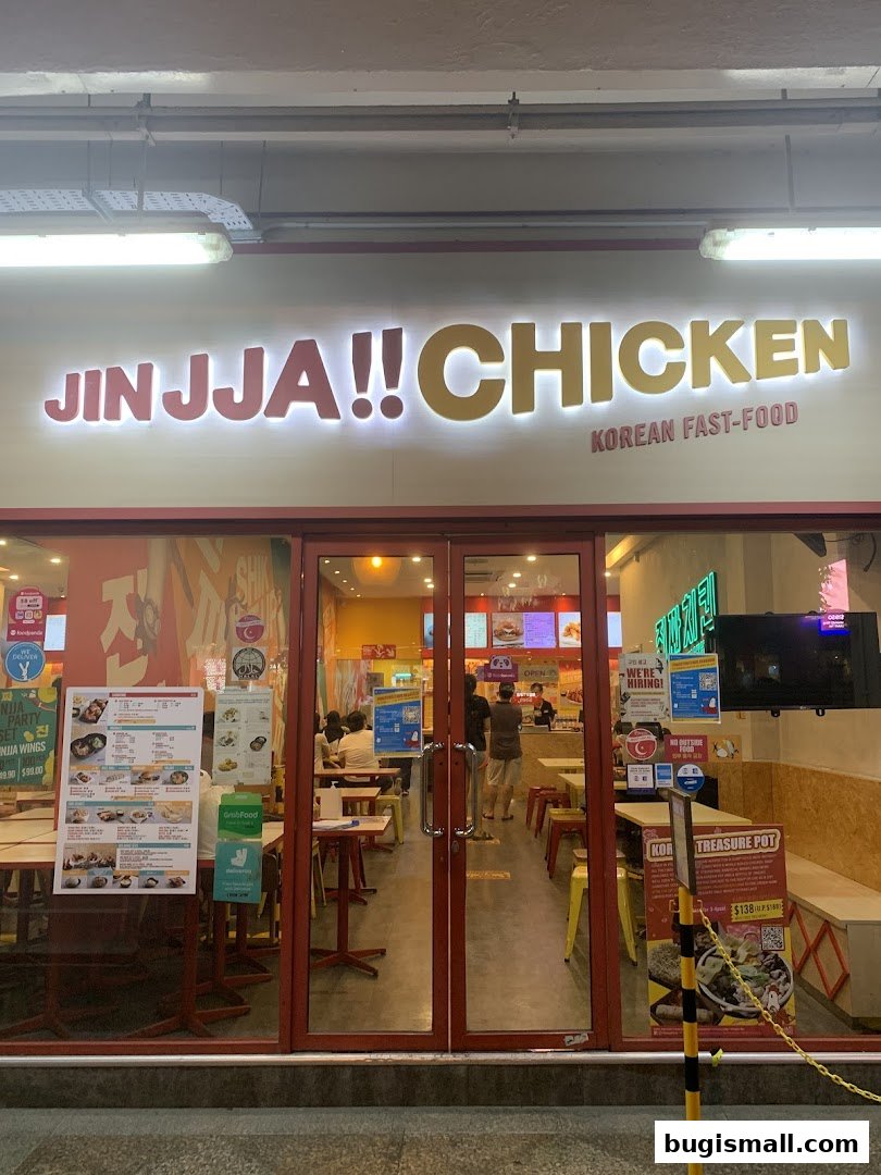The exterior of JINJJA Chicken, a Korean fast-food restaurant, with its prominent signage and entrance.