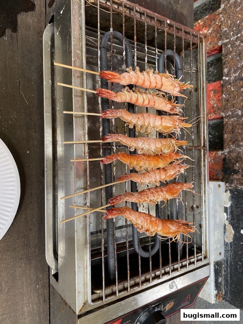 Several skewers of grilled shrimp are cooking on an electric grill.