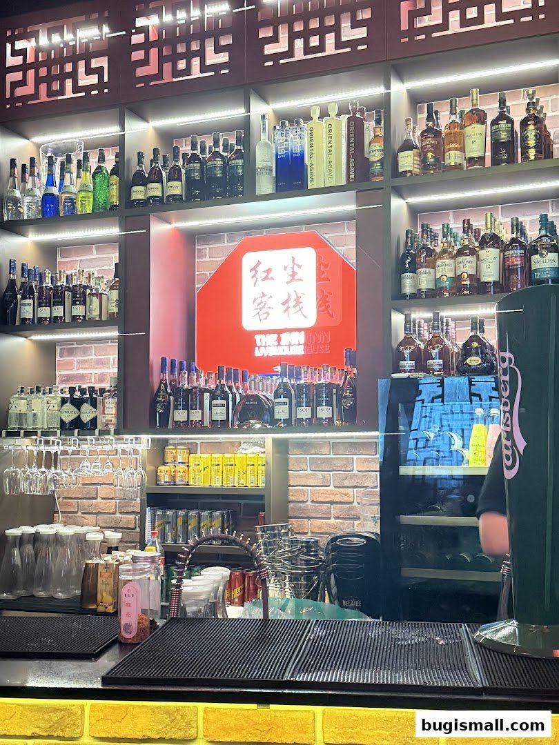 A well-stocked bar with shelves of liquor bottles, glassware, and a branded cooler.