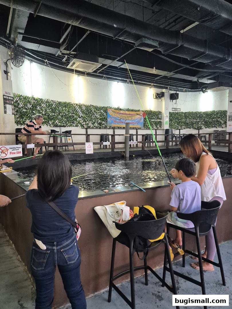 People fishing at an indoor prawn fishing pond with a competition banner.