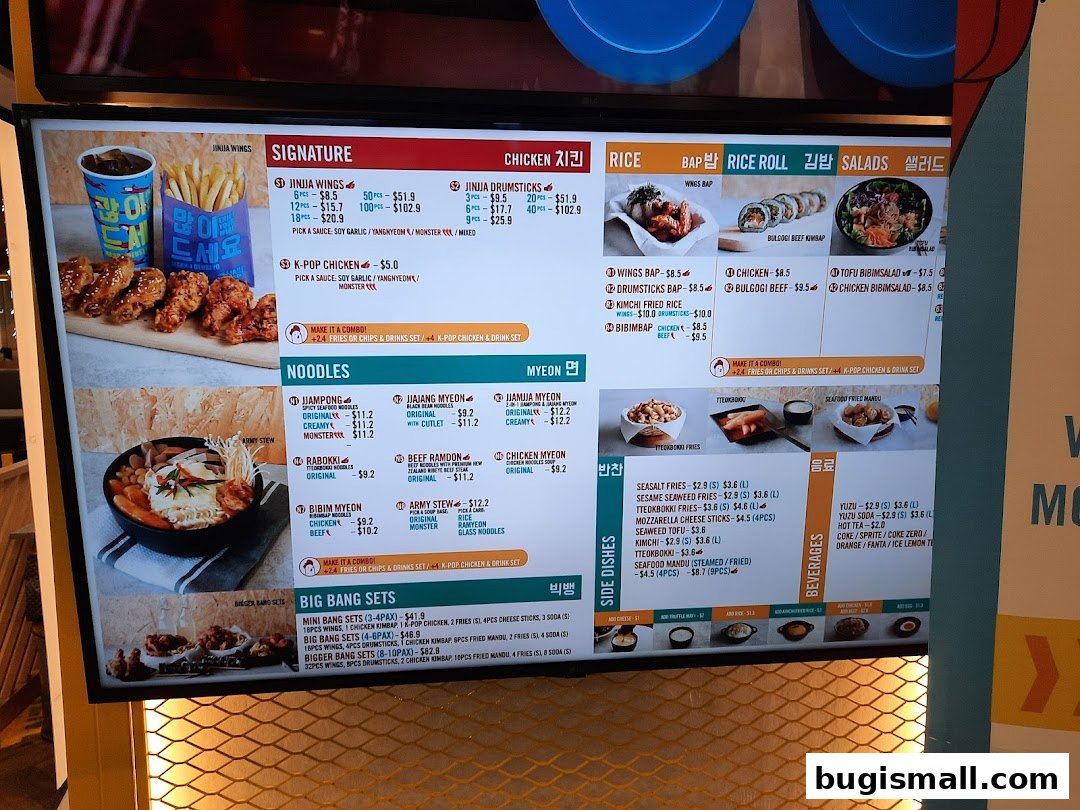 A digital menu board displaying various Korean fried chicken and noodle dishes with prices.
