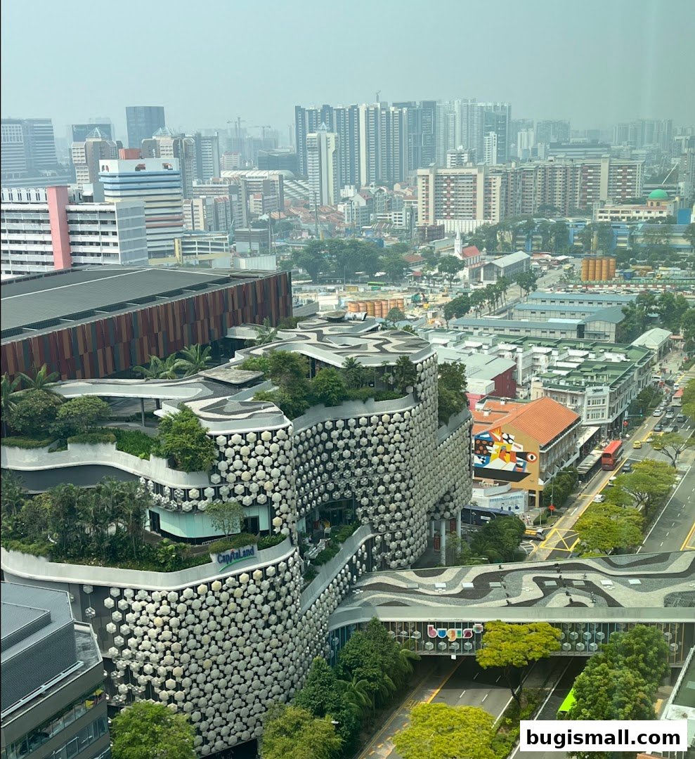 Aerial view of a modern building with unique facade and greenery, surrounded by a cityscape.