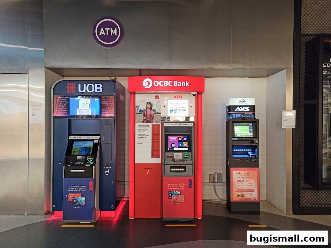 Three ATMs from UOB, OCBC Bank, and AXS are lined up in a modern retail space.