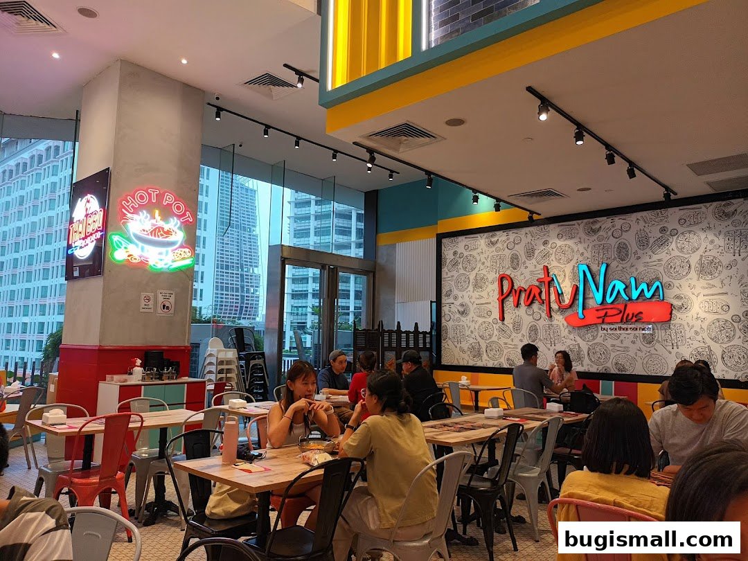Interior view of a brightly lit restaurant with diners seated at tables and a large logo on the wall.
