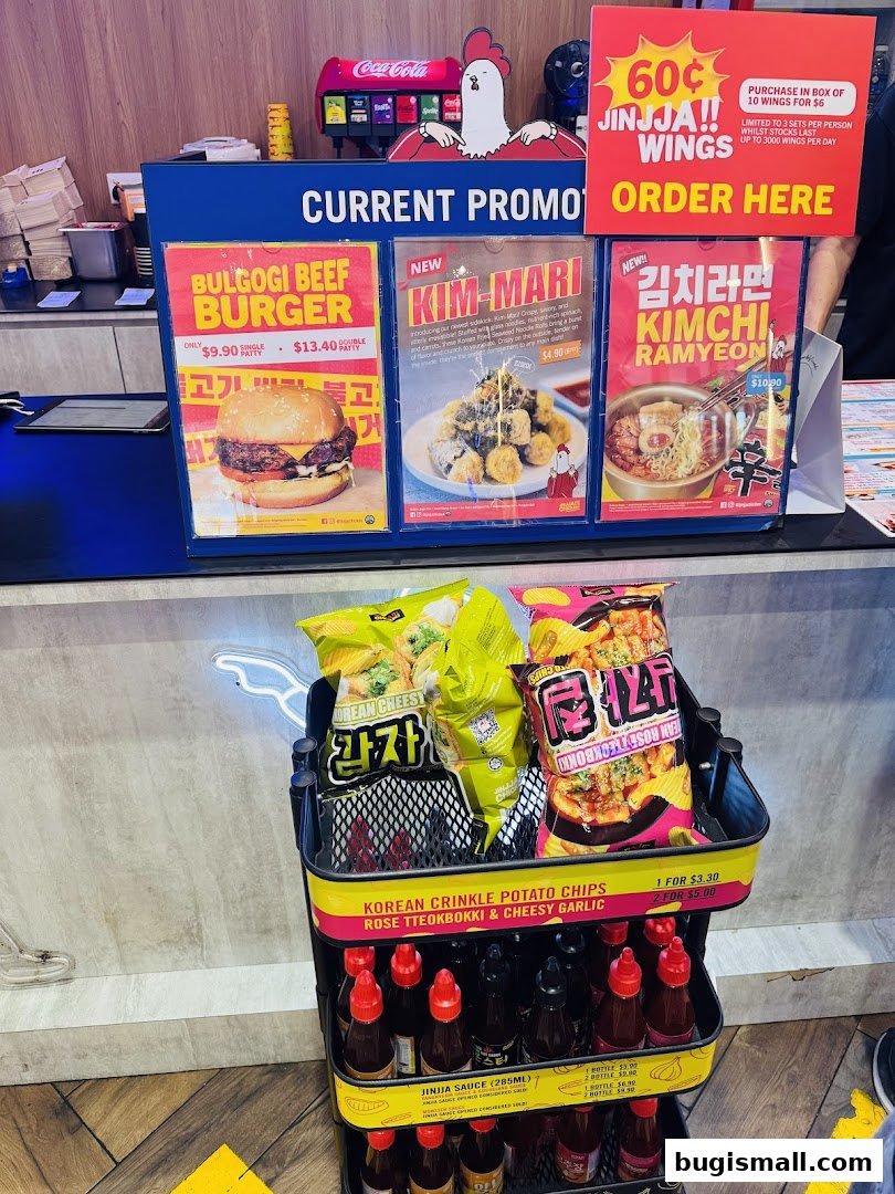 Promotional display for JINJJA Chicken featuring burgers, snacks, and sauces.