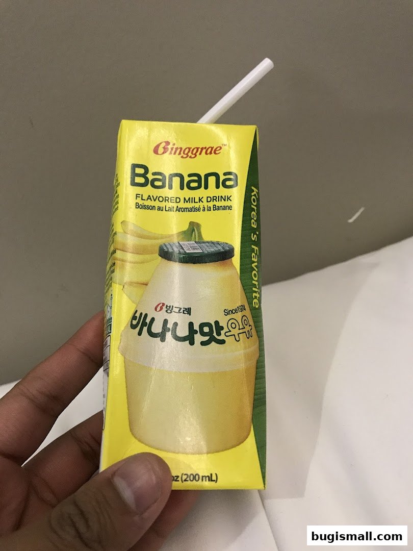 A hand holds a carton of Binggrae banana flavored milk drink.
