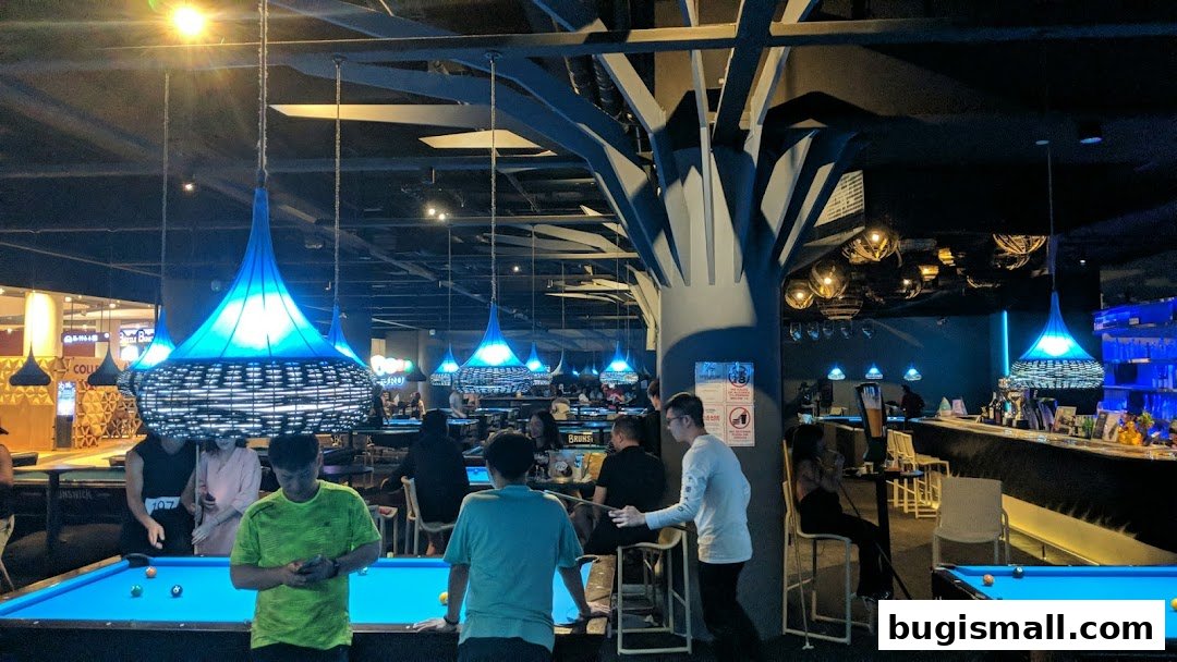 People playing pool in a dimly lit venue with striking blue pendant lights.