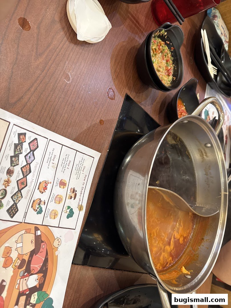 A table setting with a shabu-shabu pot, dipping sauces, and a menu.