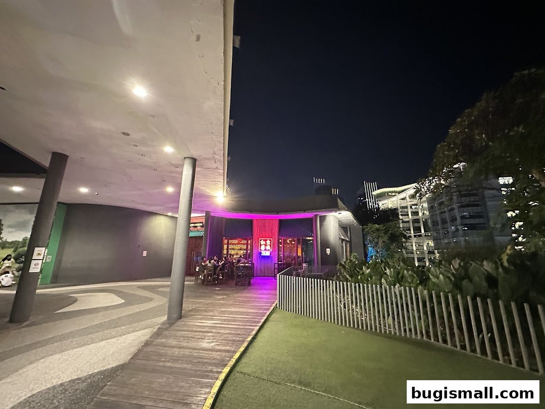 The Inn Livehouse Bugis at night, with people seated outside and vibrant pink lighting.