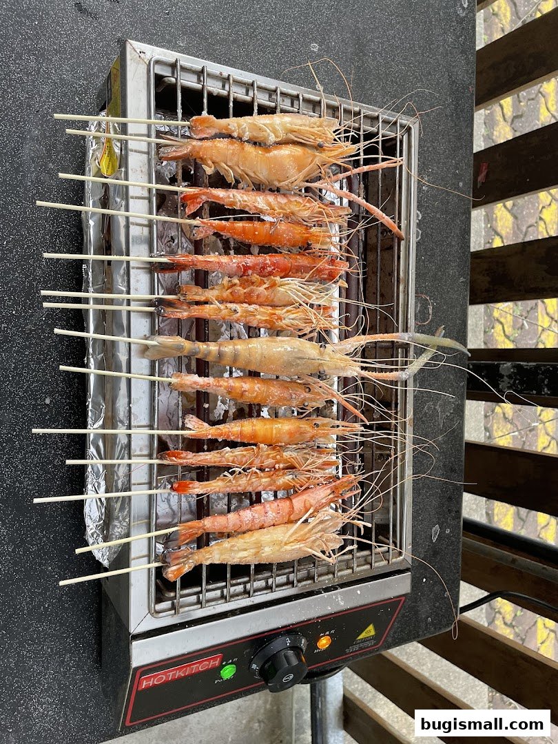 Freshly grilled prawns on skewers are displayed on a portable electric grill.