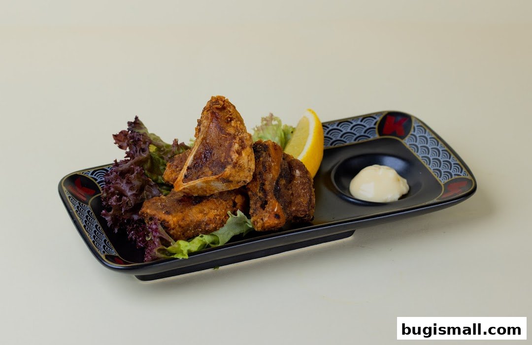 A plate of crispy fried chicken pieces with lettuce, lemon, and dipping sauce.
