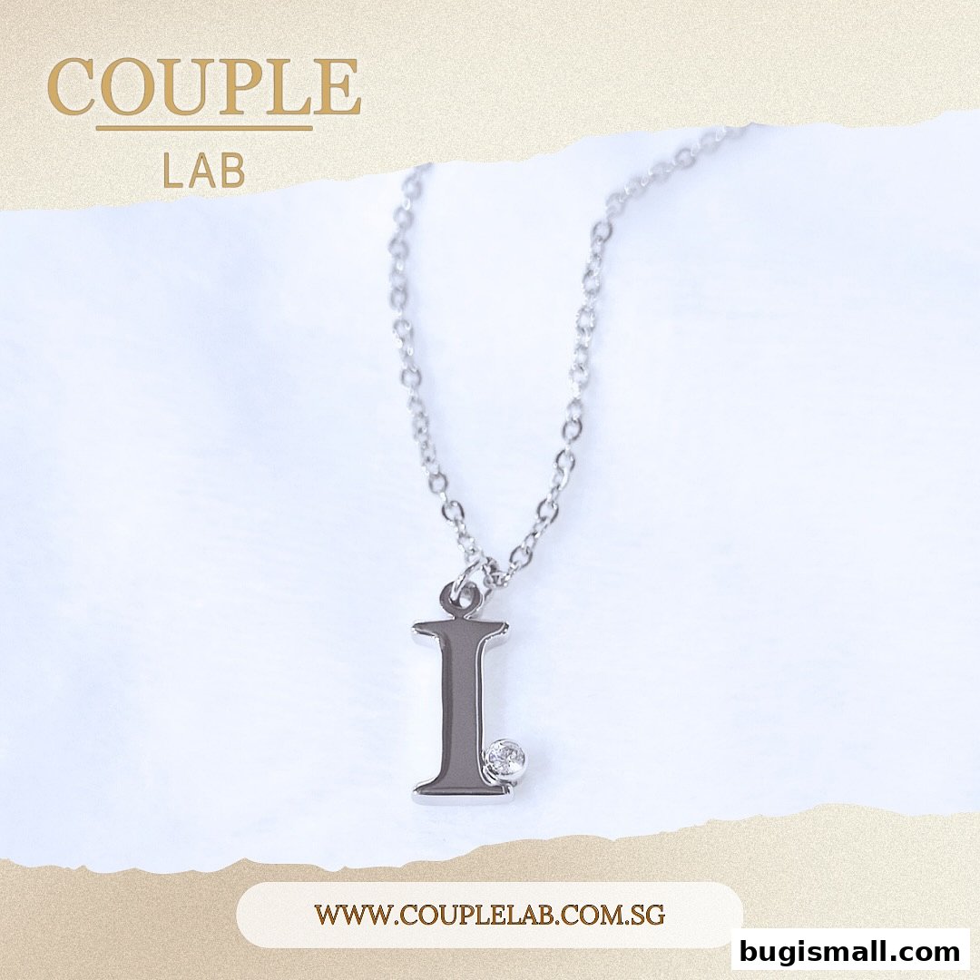 A silver necklace with an 'I' initial pendant and a small diamond.