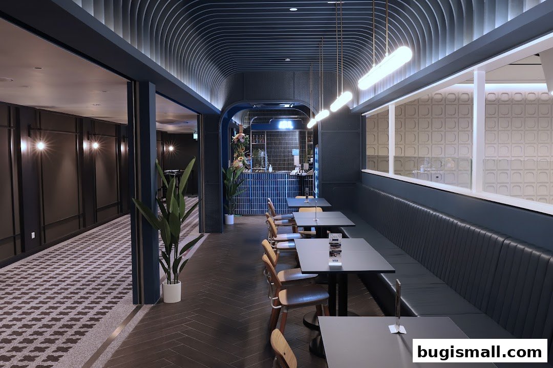 Interior of a modern restaurant with dark seating, tables, and a bar area.