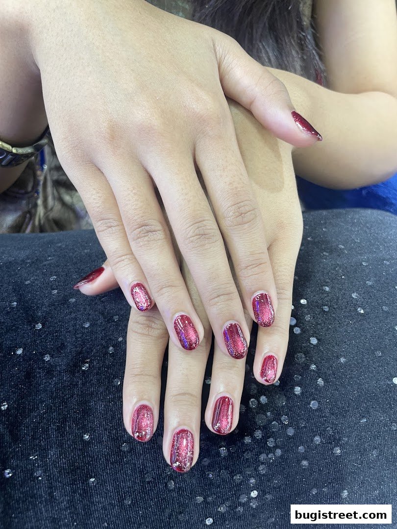 Close-up of hands with beautifully manicured nails painted in a shimmering red polish.