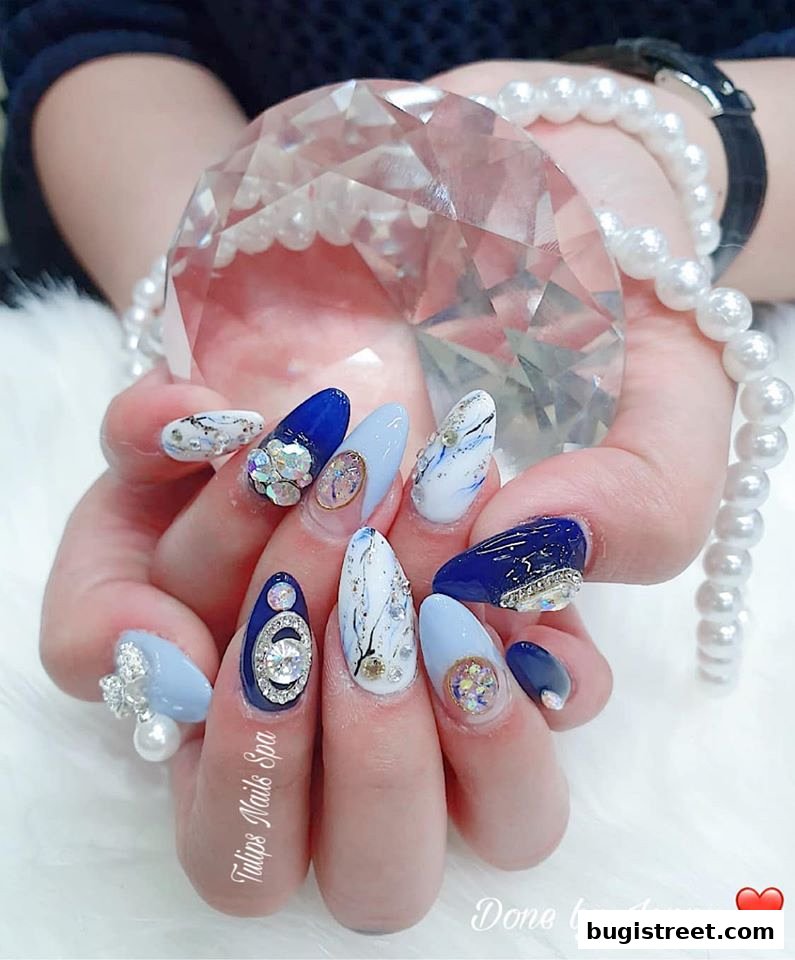 A close-up of hands with elaborately decorated nails, holding a large crystal.