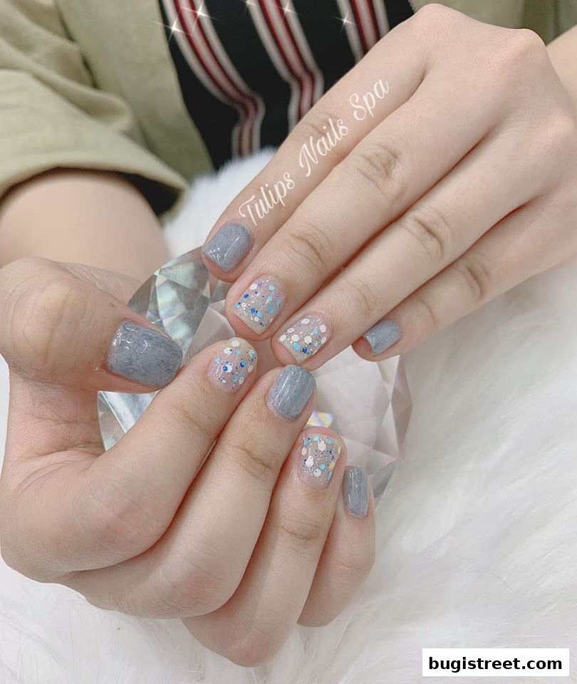 A close-up of hands with stylish grey and glitter nail art from Tulips Nails Spa.