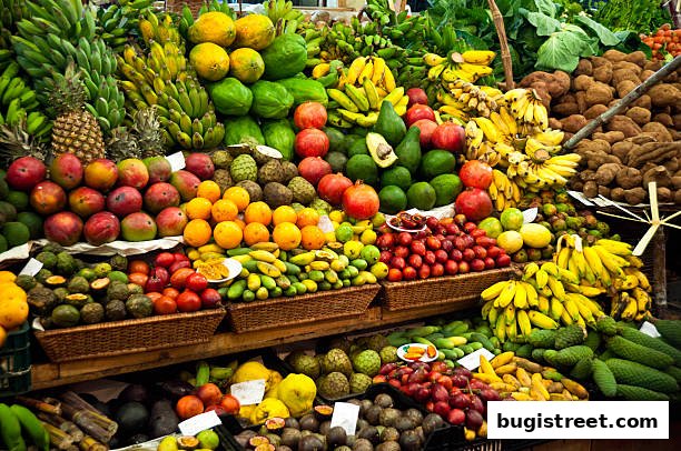 A vibrant display of fresh fruits and vegetables, including bananas, pineapples, mangoes, and pomegranates.