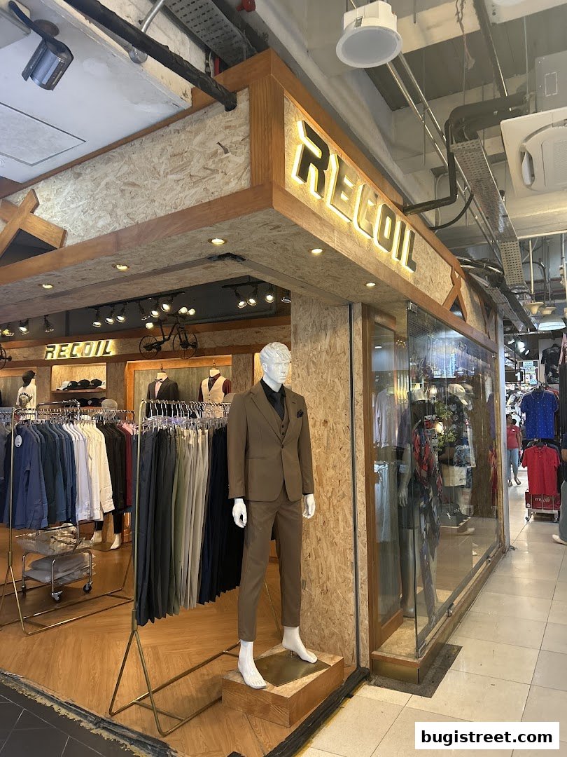 A well-lit shop front displaying men's suits and apparel with a mannequin.