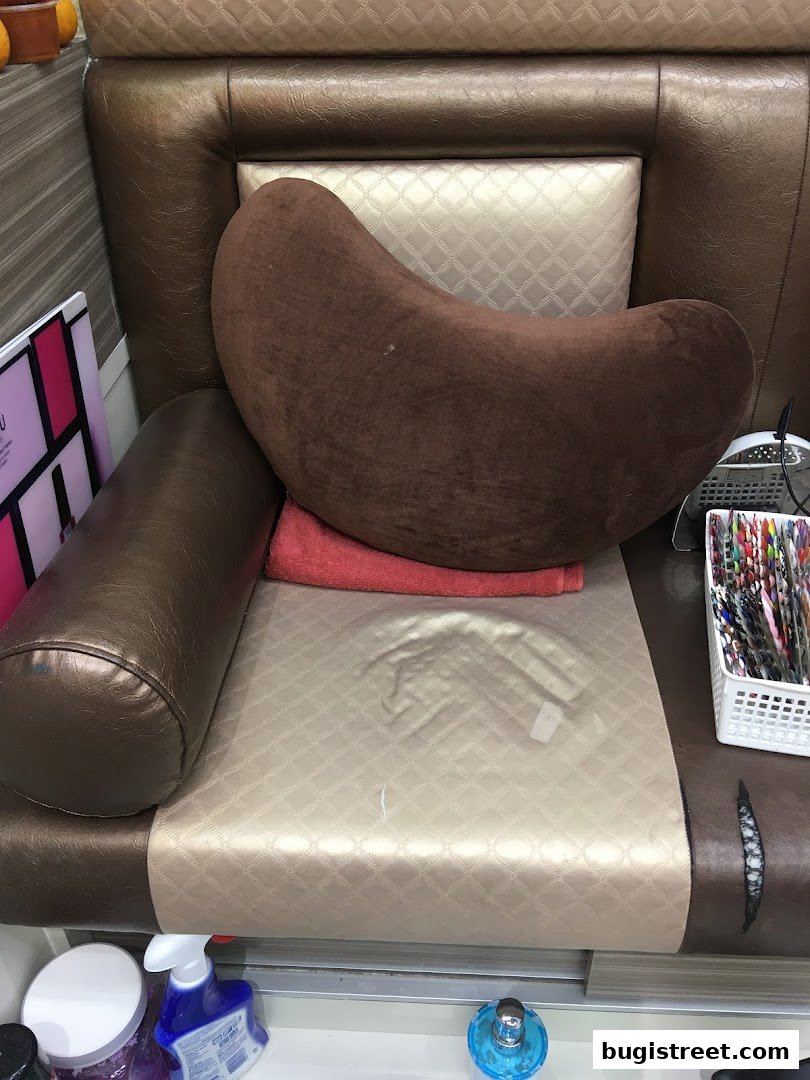 A close-up of a comfortable nail spa chair with plush cushions and nail art supplies.