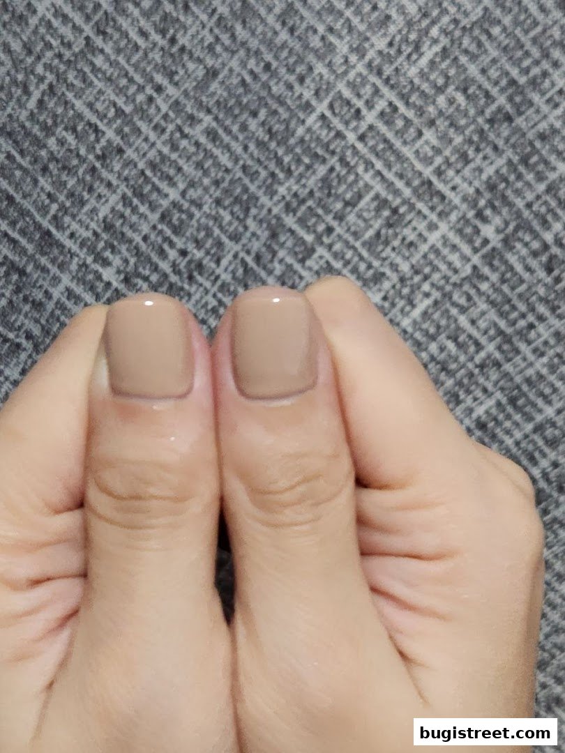 Close-up of two hands with neatly manicured nails painted in a neutral beige color.