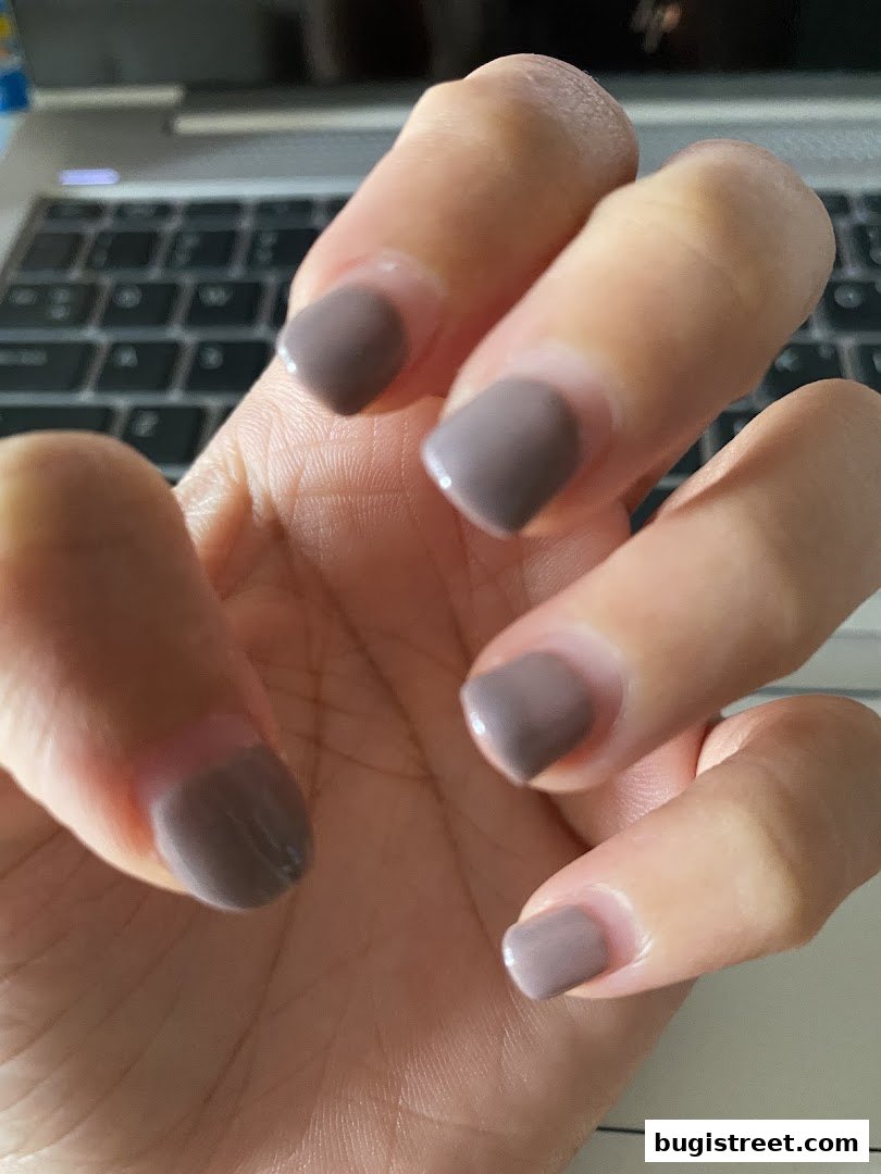 Close-up of a hand with neatly manicured nails painted in a muted taupe color.