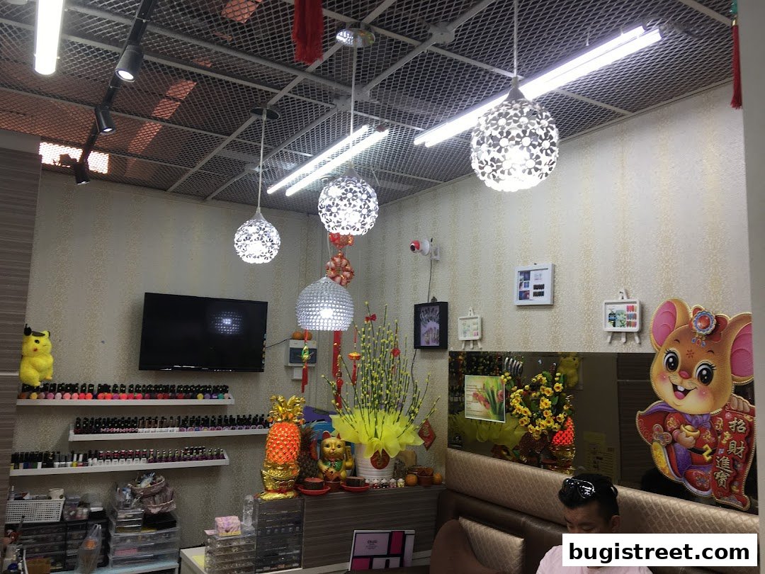 Interior of a nail spa with shelves of nail polish, decorative items, and a seated customer.