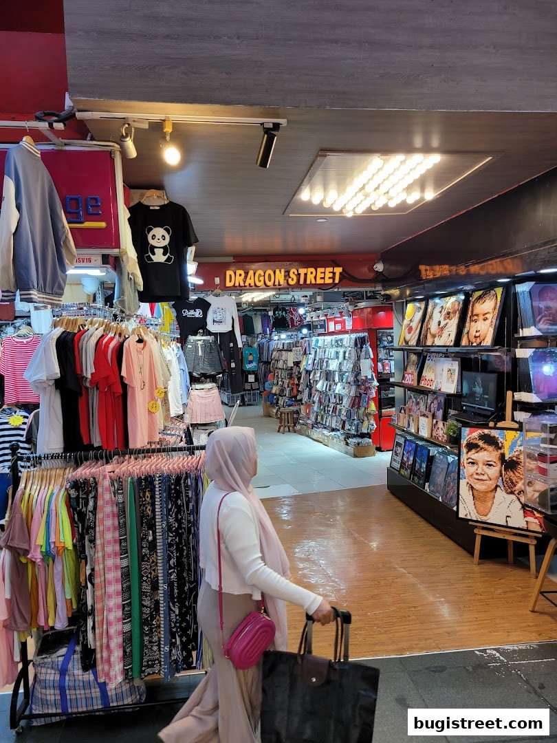 A woman walks past racks of colorful clothing and displays of art in a shop.