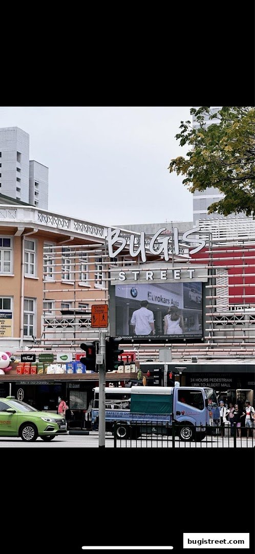A street view of Bugis Street with shops, traffic lights, and a truck.