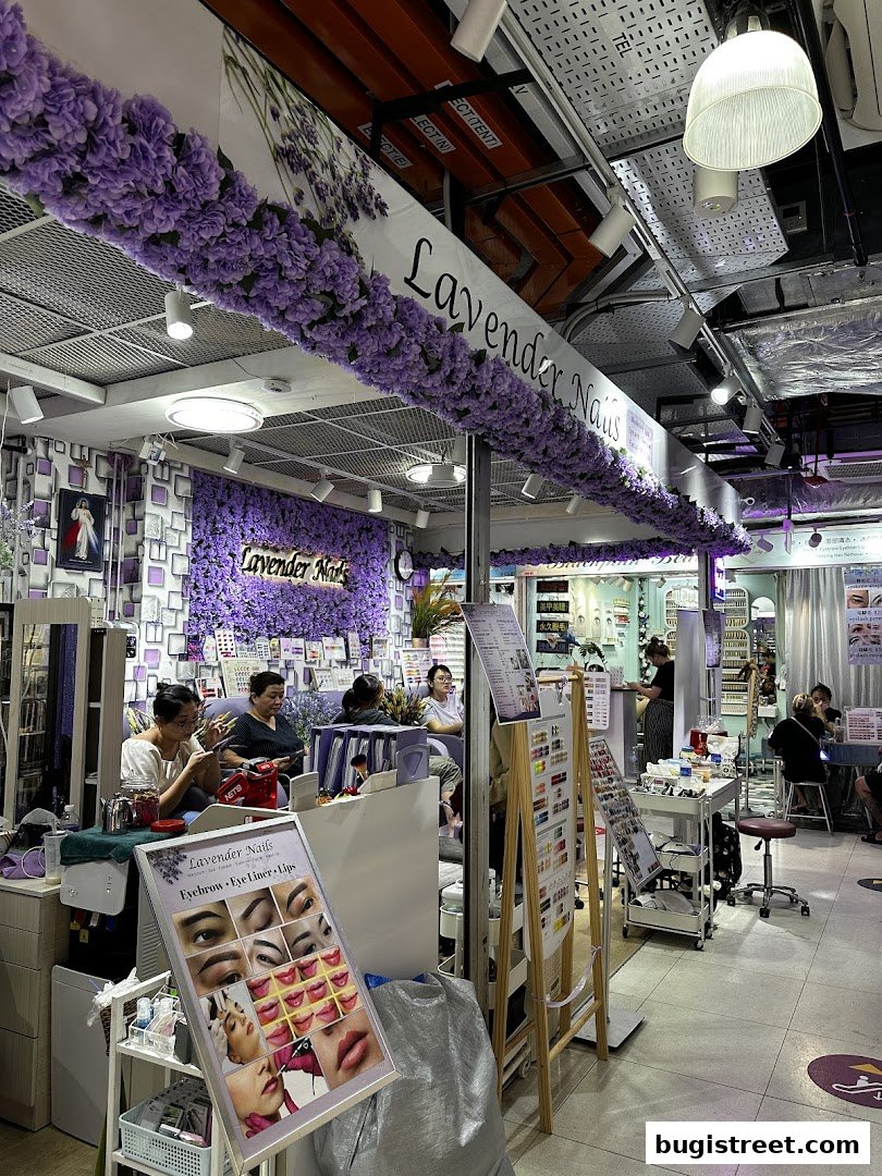 Interior of a nail salon with customers receiving services and displays of nail art.