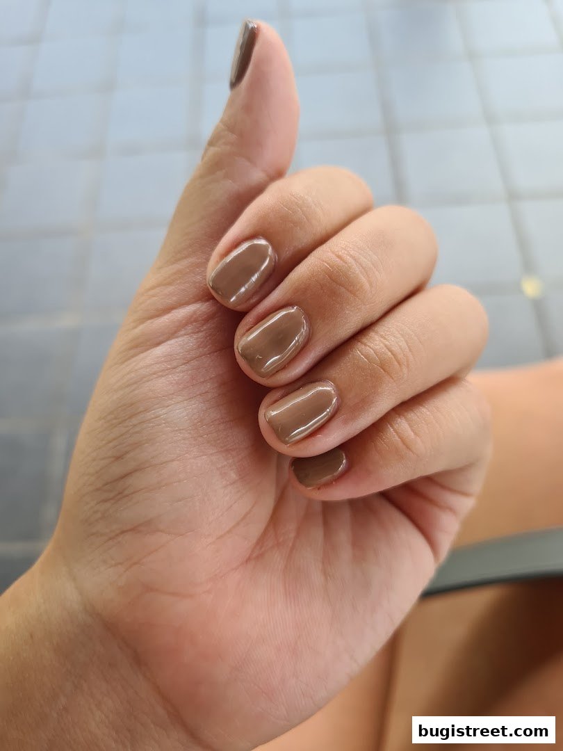 A close-up shot of a hand with perfectly manicured nails painted in a chic brown shade.