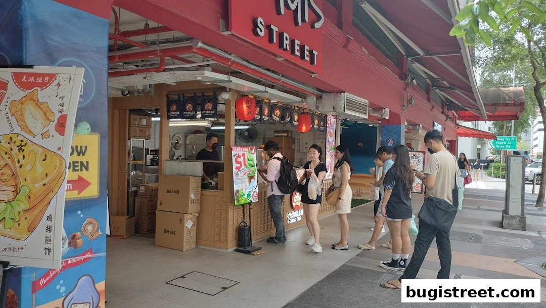 A street-side food stall with customers ordering and staff serving. The shop is called 'MIS STREET'.