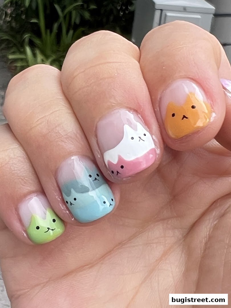 Close-up of hands with adorable cat-themed nail art in pastel colors.