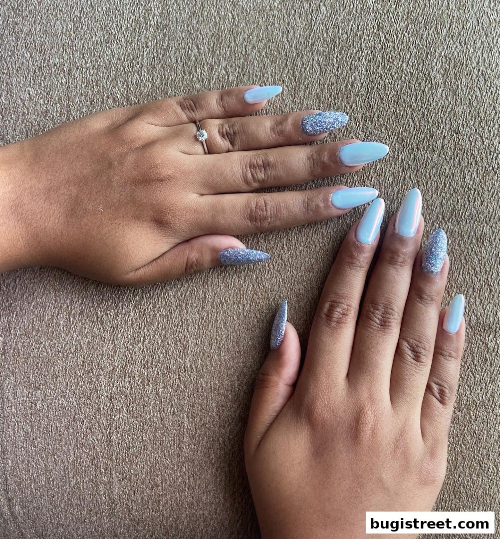 Close-up of two hands with light blue and glittery stiletto-shaped acrylic nails.