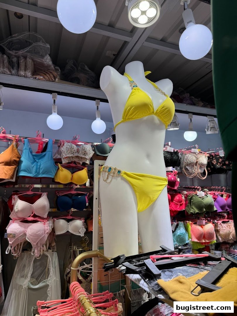 A mannequin displays a yellow bikini, surrounded by racks of bras and lingerie.