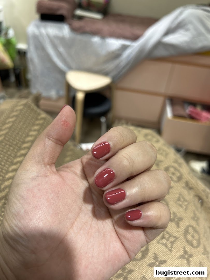A hand with freshly painted, glossy, reddish-brown nails.