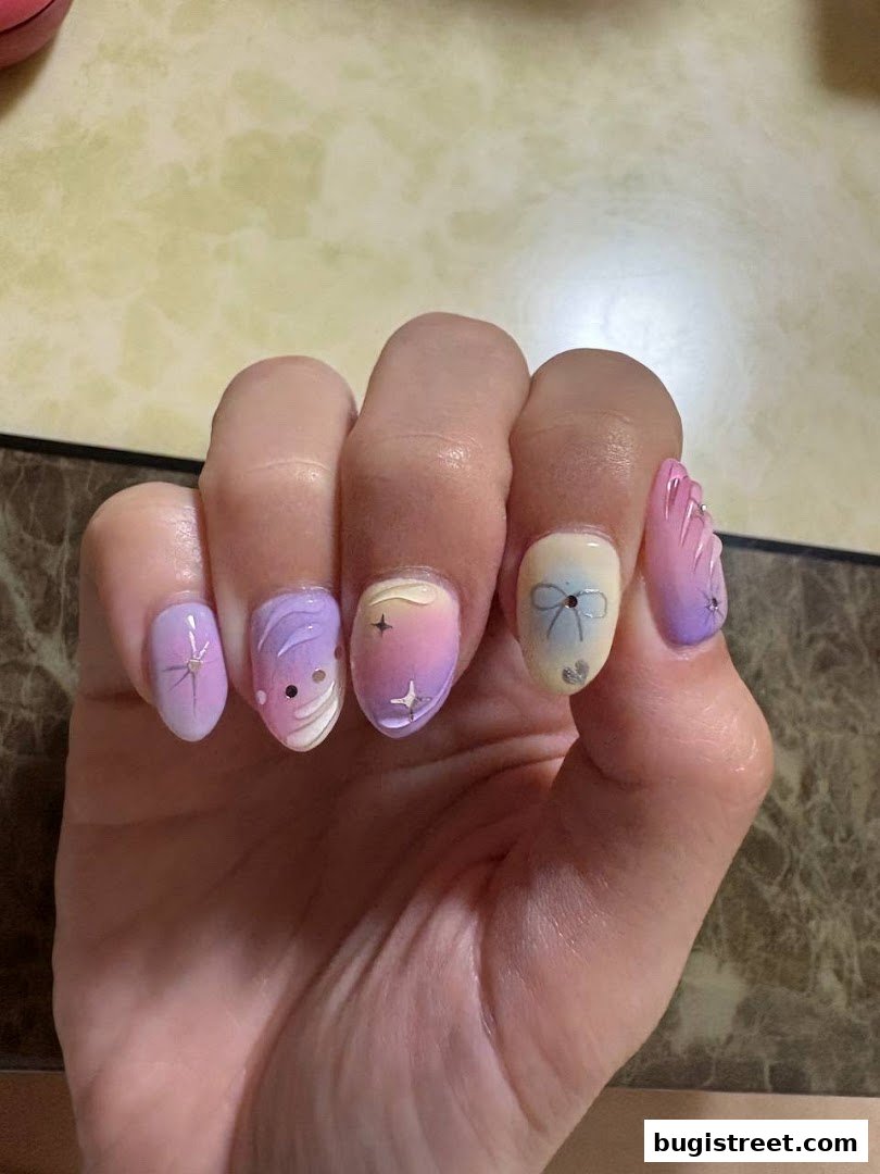 A close-up of a hand displaying beautifully designed nails with pastel colors and intricate patterns.