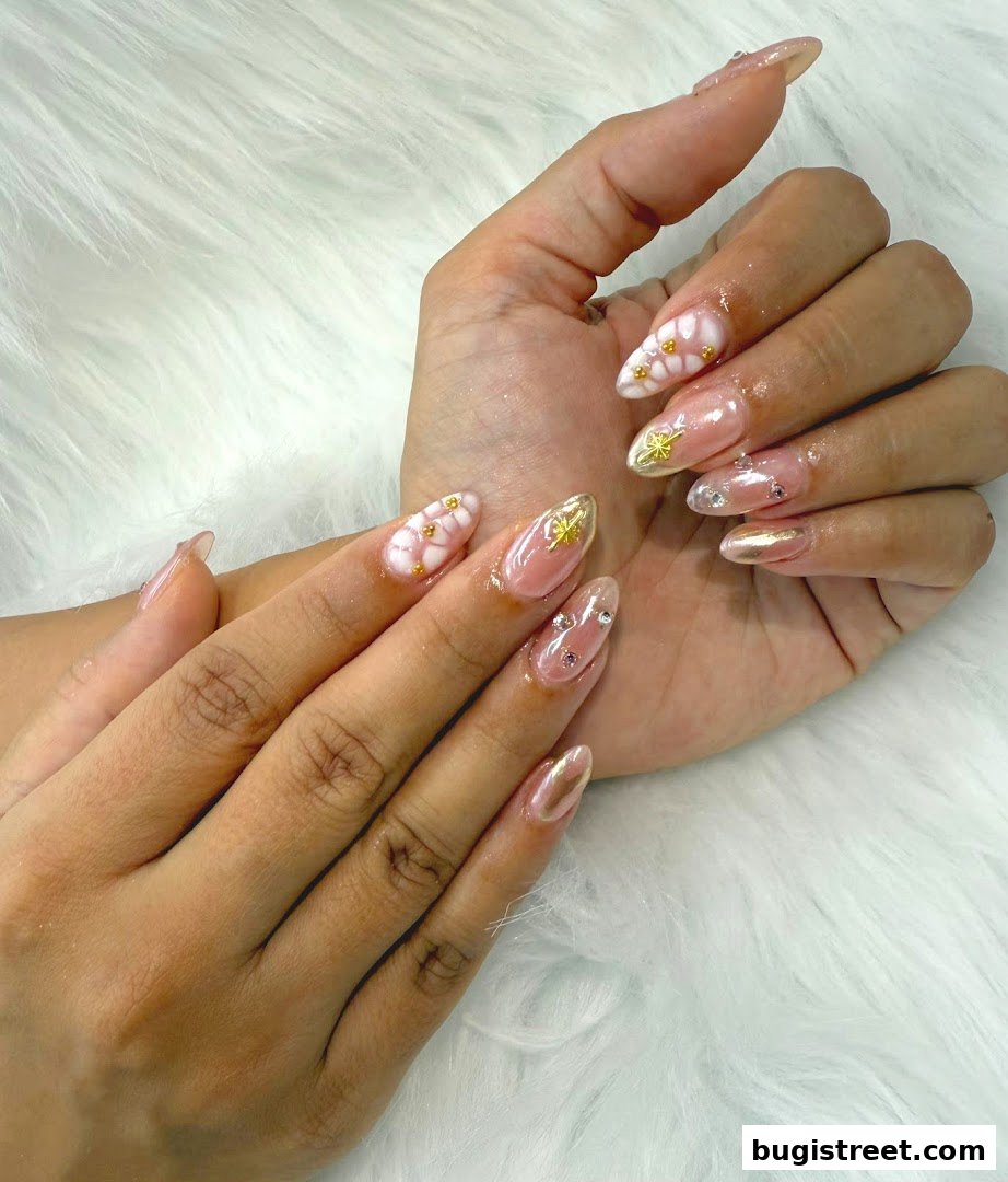 Close-up of hands with beautifully decorated almond-shaped nails featuring floral designs and gems.