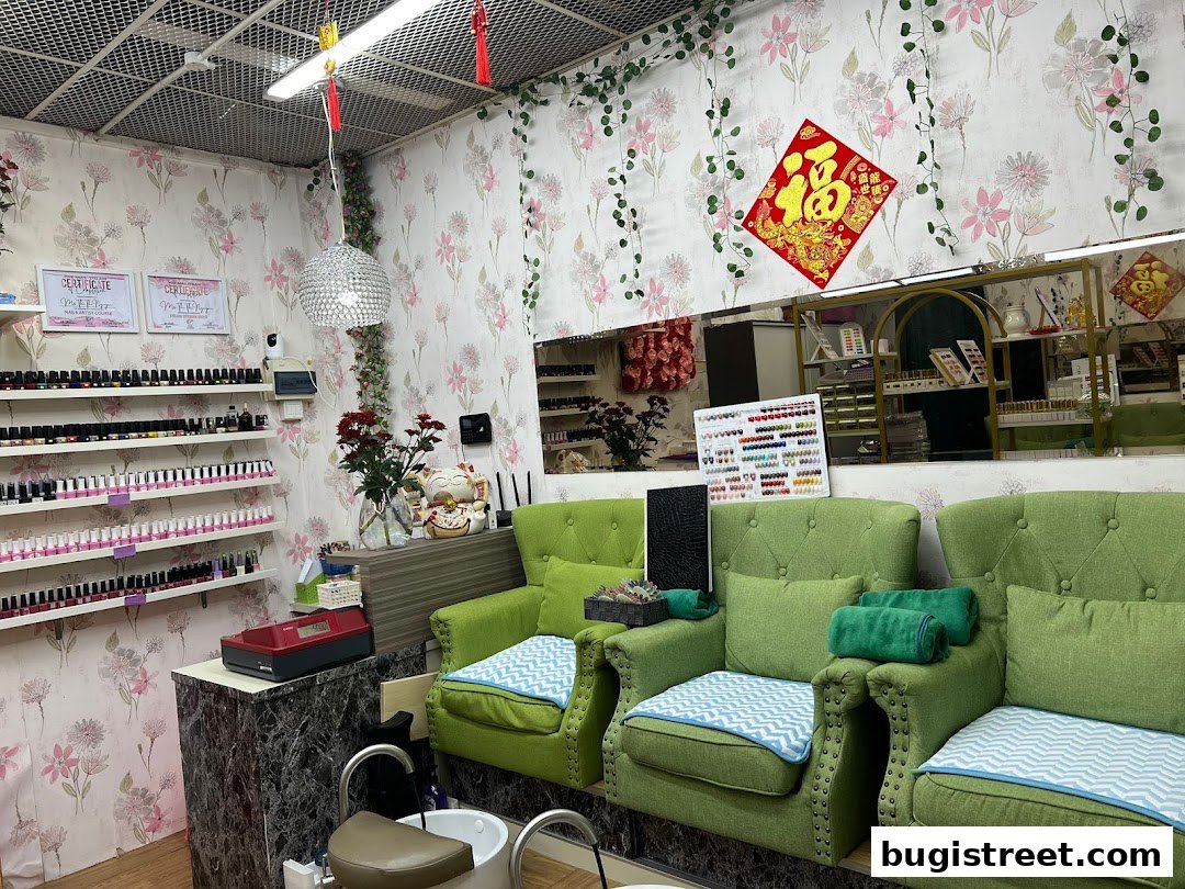 Interior of a nail salon with green chairs, shelves of nail polish, and floral wallpaper.