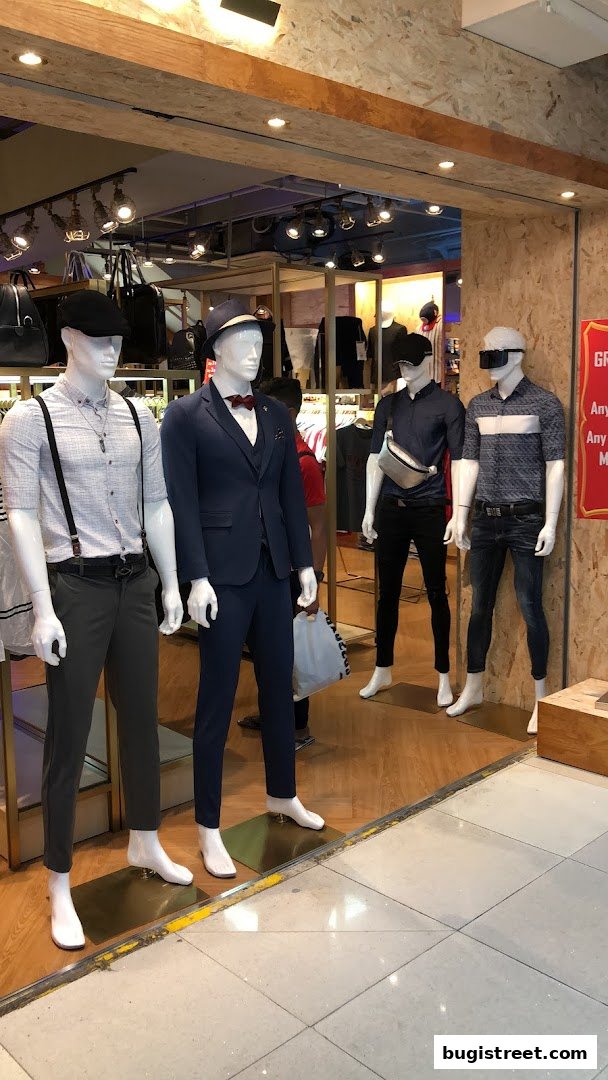 Mannequins dressed in stylish menswear are displayed at the entrance of a clothing store.