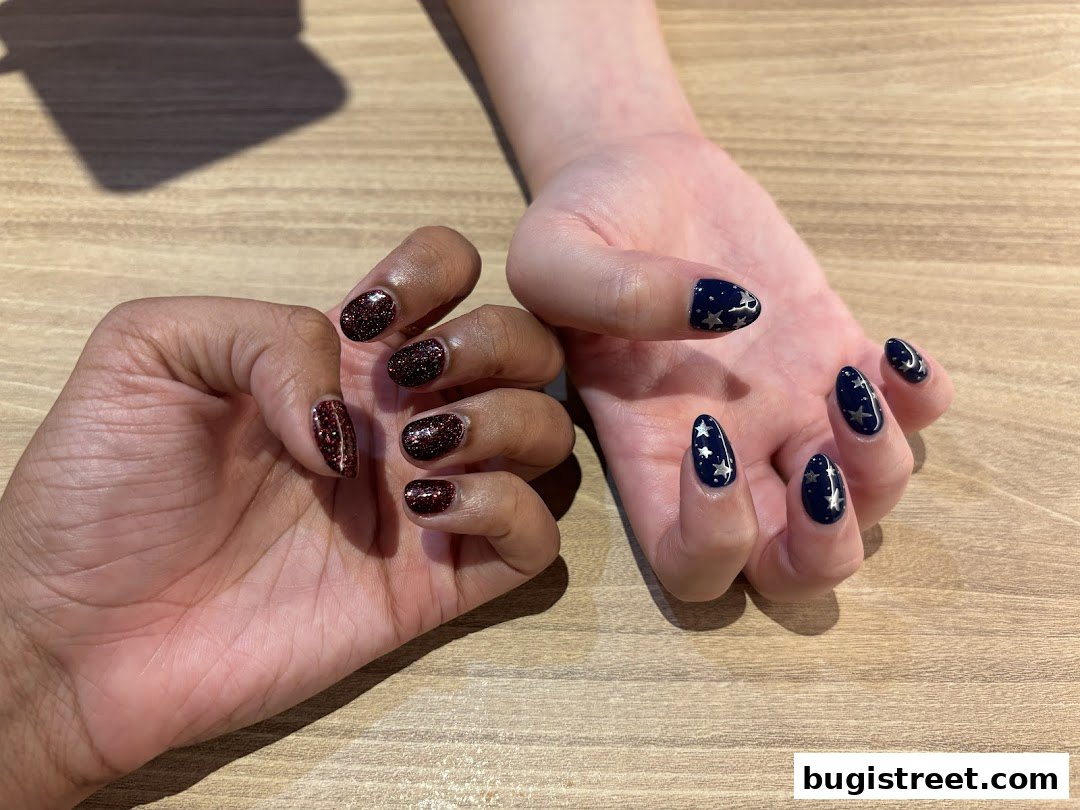 Close-up of two hands showcasing beautifully manicured nails with glitter and star designs.