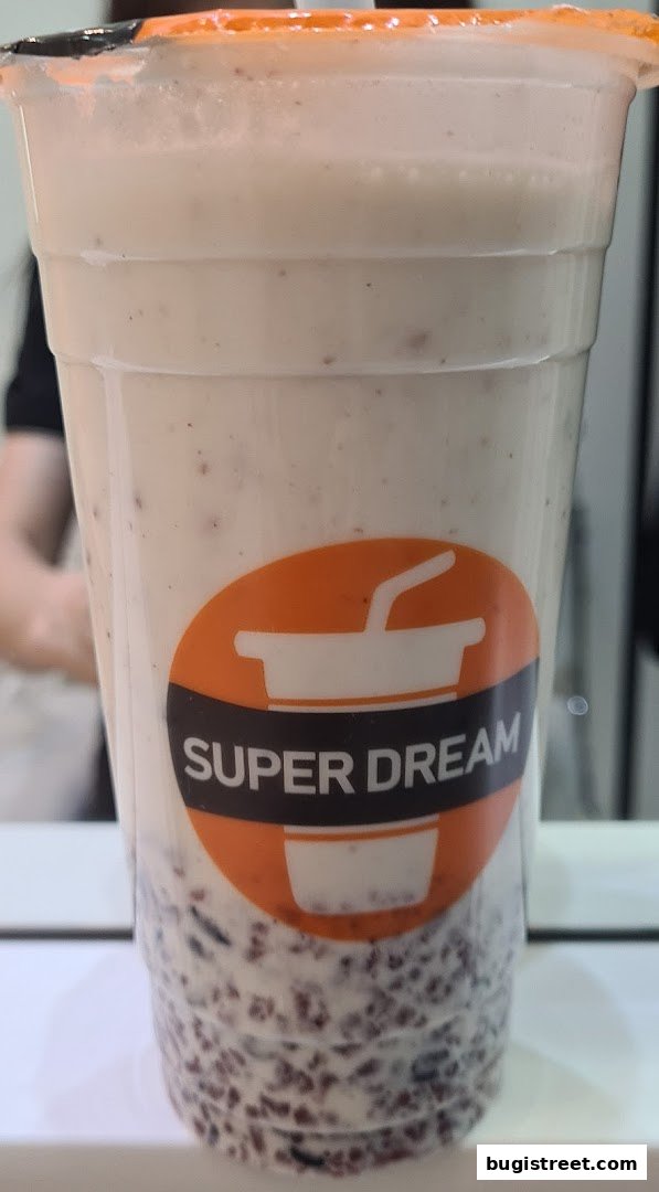 A close-up of a drink from Super Dream with visible ingredients at the bottom.