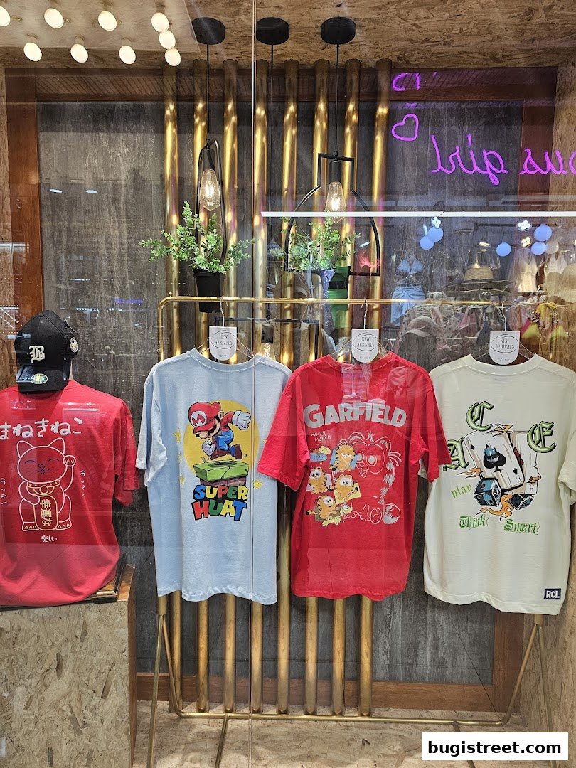 A shop window displays four graphic t-shirts and a baseball cap.