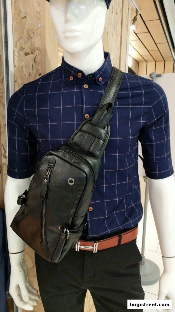 Mannequin wearing a blue checkered shirt, black pants, and a black sling bag.