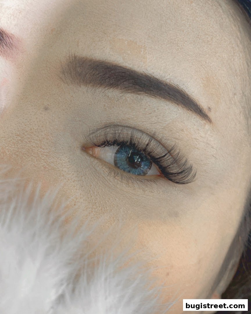 Close-up of a woman's eye with dramatic false eyelashes and blue contact lenses.