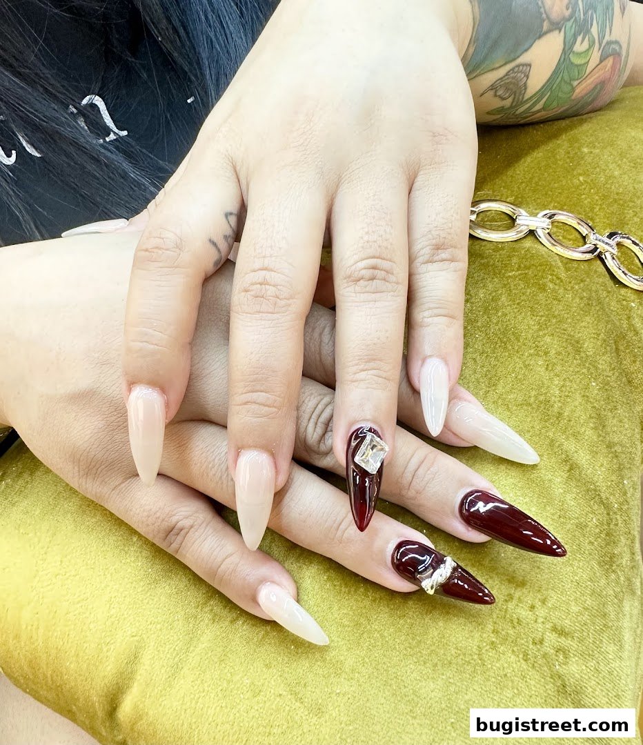 Close-up of hands with elegantly designed stiletto nails in nude and deep red.