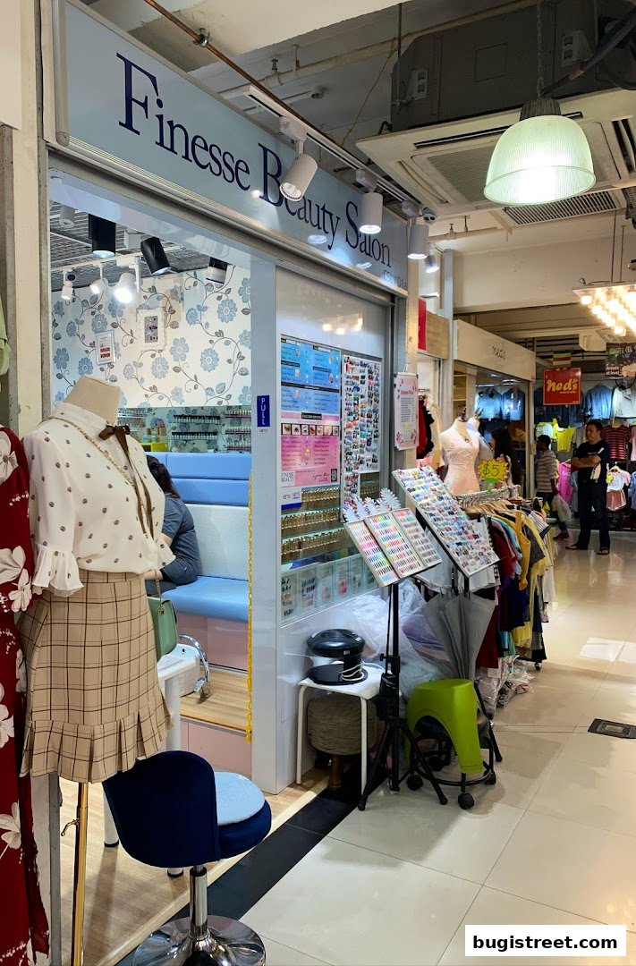 A beauty salon shop front displaying nail polish colors and clothing mannequins.