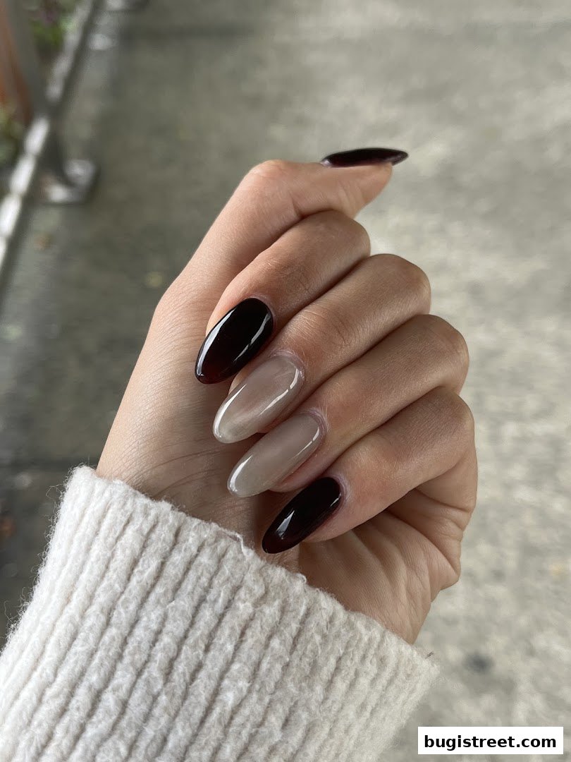 A hand with elegantly styled nails in dark brown and nude shades.