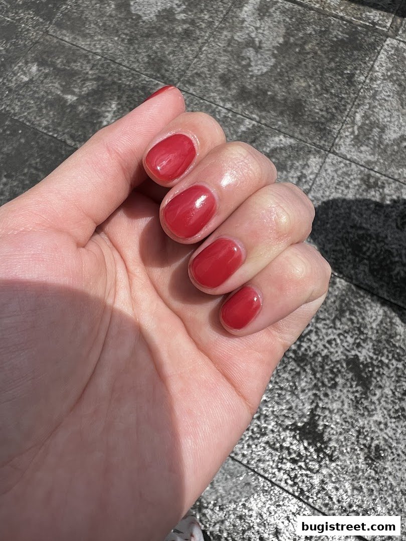 A close-up of a hand with perfectly manicured, glossy red nails.