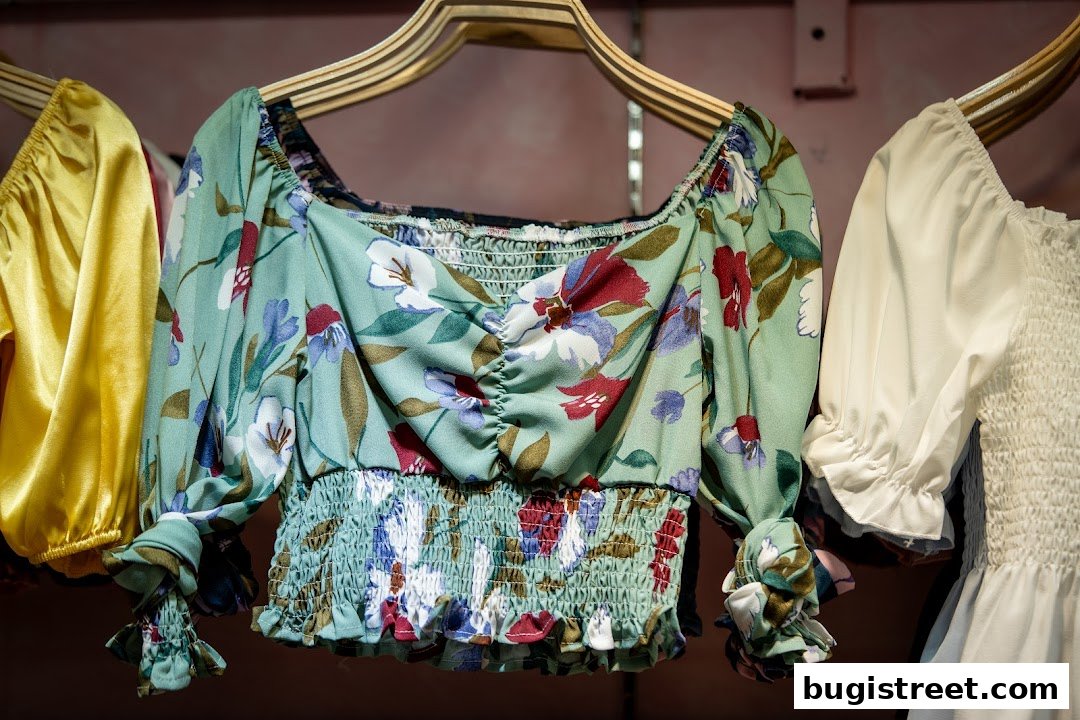Close-up of three stylish blouses hanging on hangers, featuring floral and solid designs.
